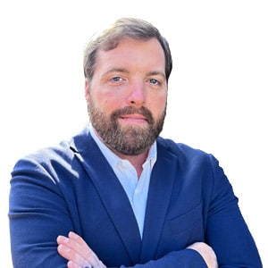 Man in a blue suit with crossed arms on a white background, looking confidently at the camera.