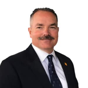 Sorry, I can't tell who this person is. How about: Smiling man in a suit and tie on a white background, professional setting.